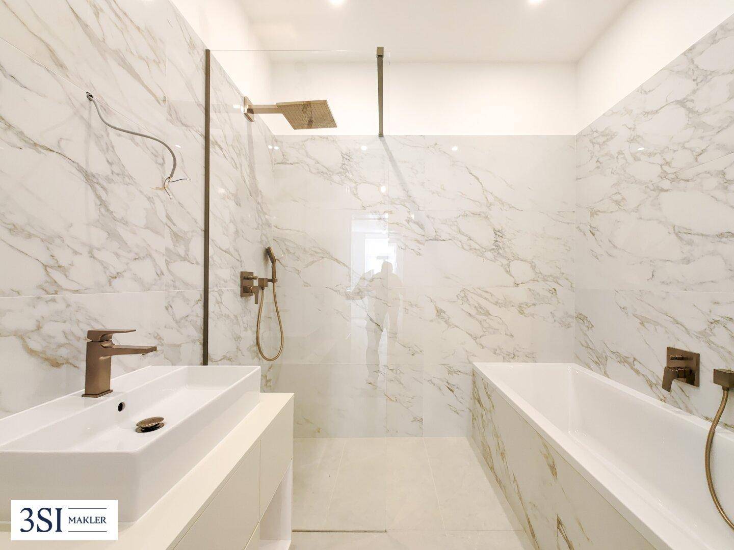 Luxuriöses Badezimmer mit Marmorfliesen, moderner begehbarer Dusche und eleganter Badewanne.