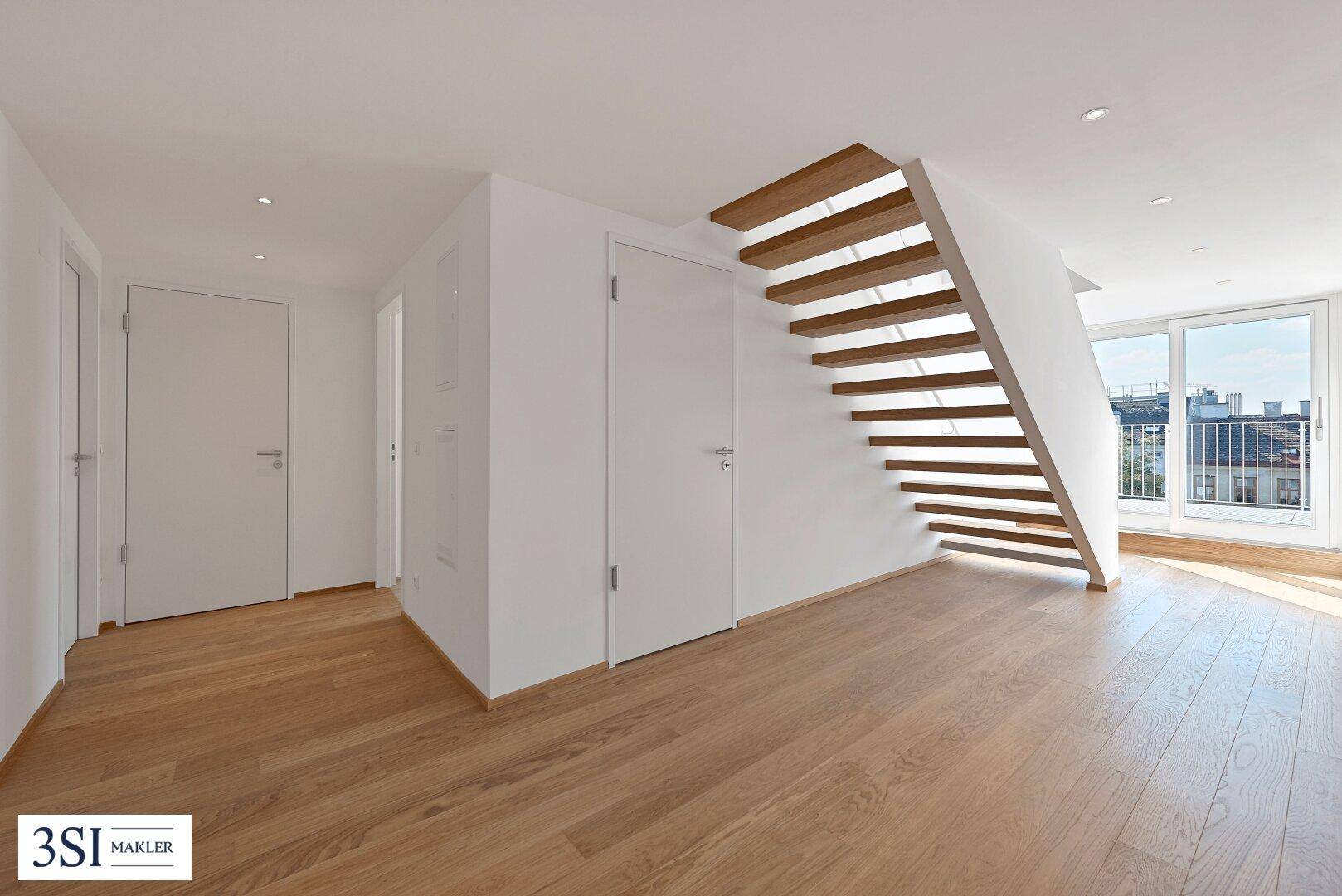 Heller Flur mit Holzboden und offener Treppe, der zu den oberen Etagen führt.