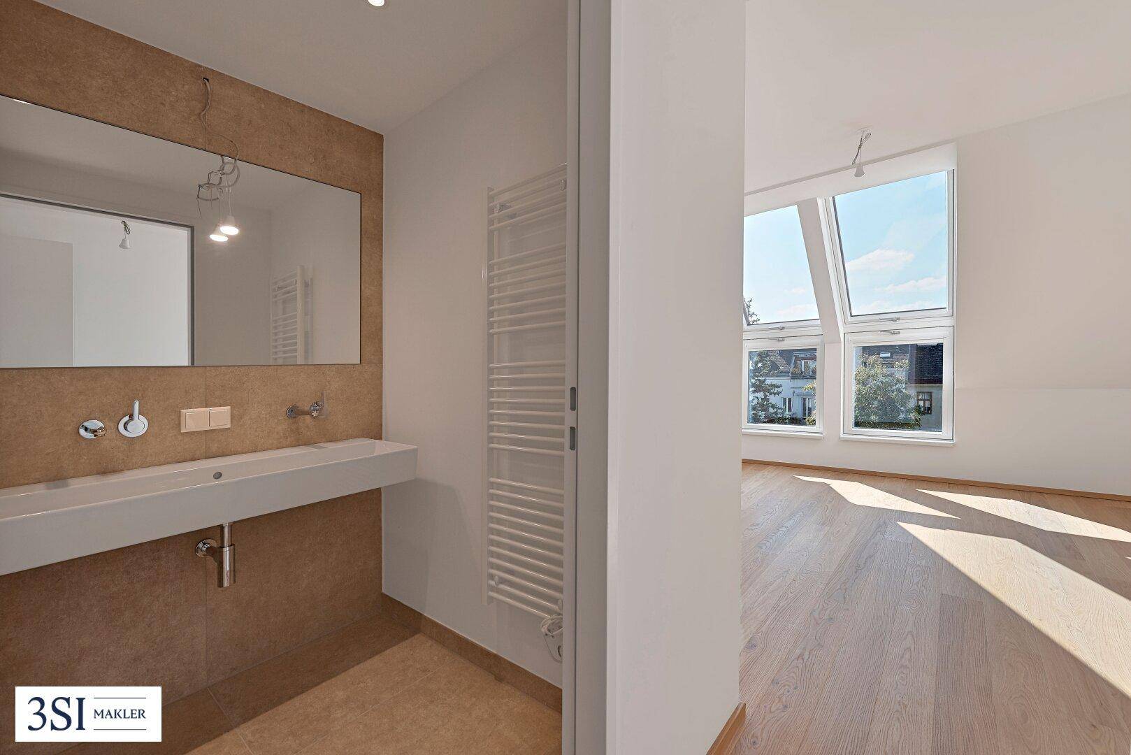 Modernes Badezimmer mit Einzelwaschbecken, Handtuchheizkörper und Blick in einen hellen Raum.