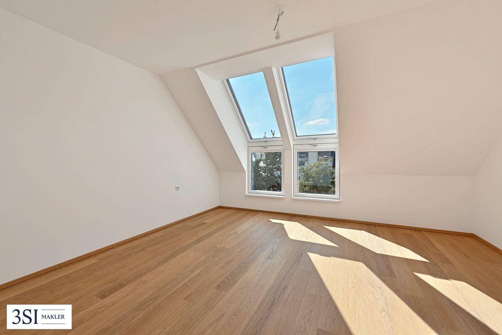 Unmöbliertes Zimmer mit Holzboden, Dachfenstern und viel Tageslicht.