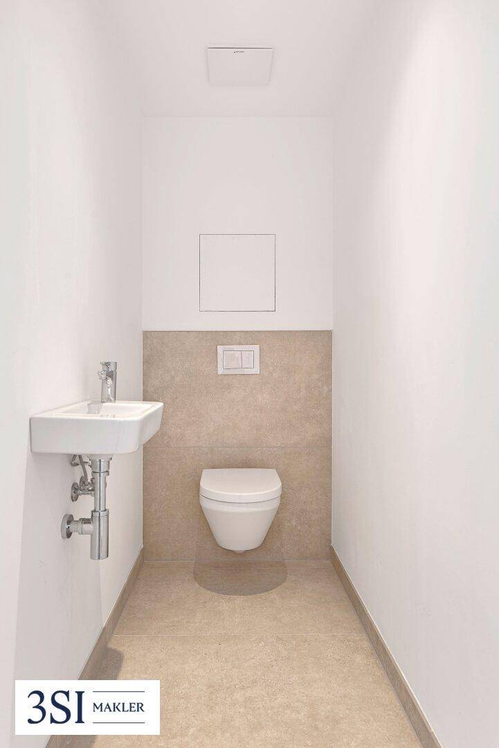 Modernes Gäste-WC mit wandhängender Toilette und kleinem Waschbecken.