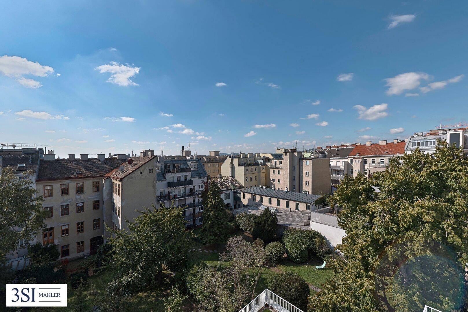 Weitläufiger Blick über die Dächer der Stadt mit viel Grün und historischen Gebäuden.