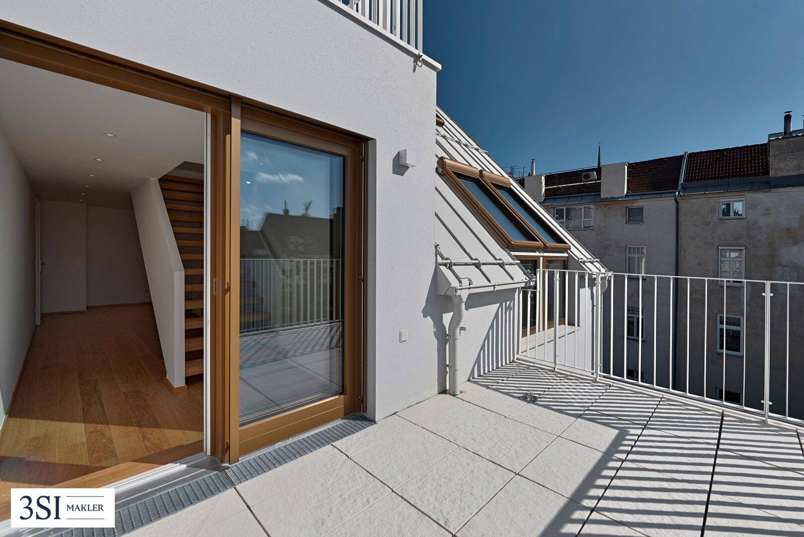 Dachterrasse mit Zugang vom Innenraum und Blick auf die Stadt.