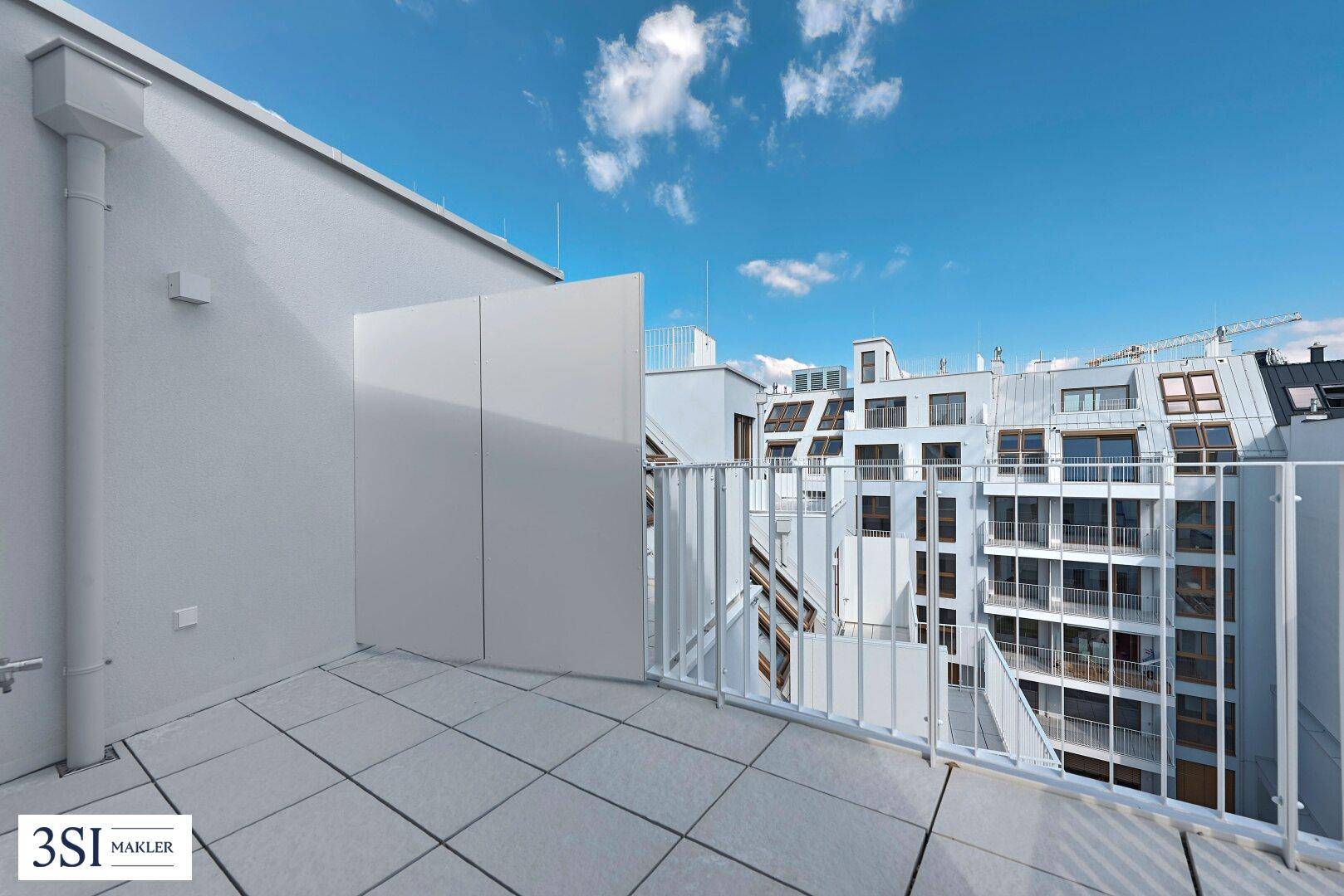 Langer, schmaler Balkon mit Fliesenboden und Blick auf die umliegenden Gebäude.