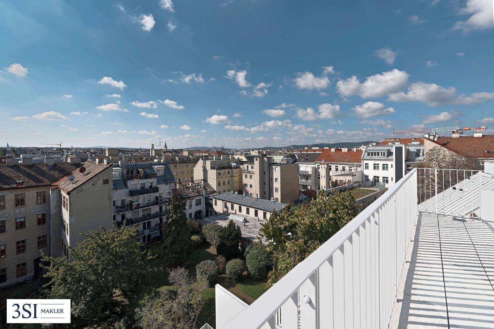 Weitläufige Dachterrasse mit Panoramablick über die Stadt und grüne Innenhöfe.