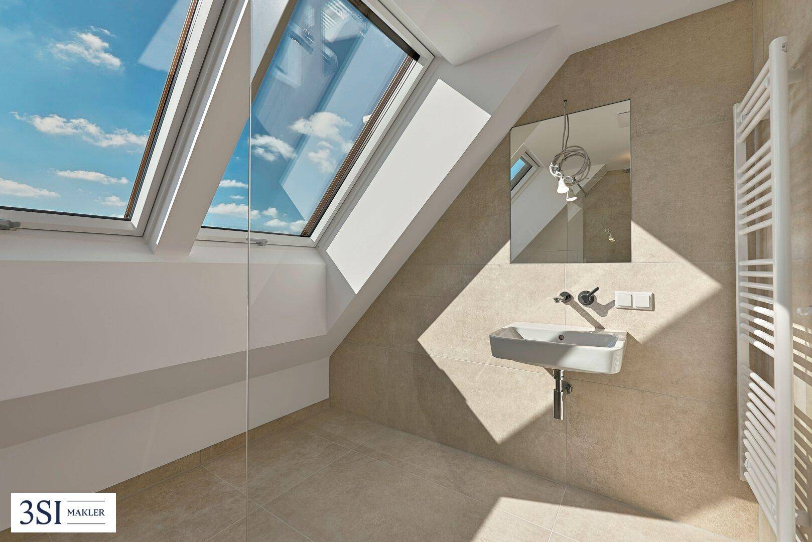 Modernes Badezimmer mit Einzelwaschbecken, Handtuchheizkörper und schrägen Dachfenstern.