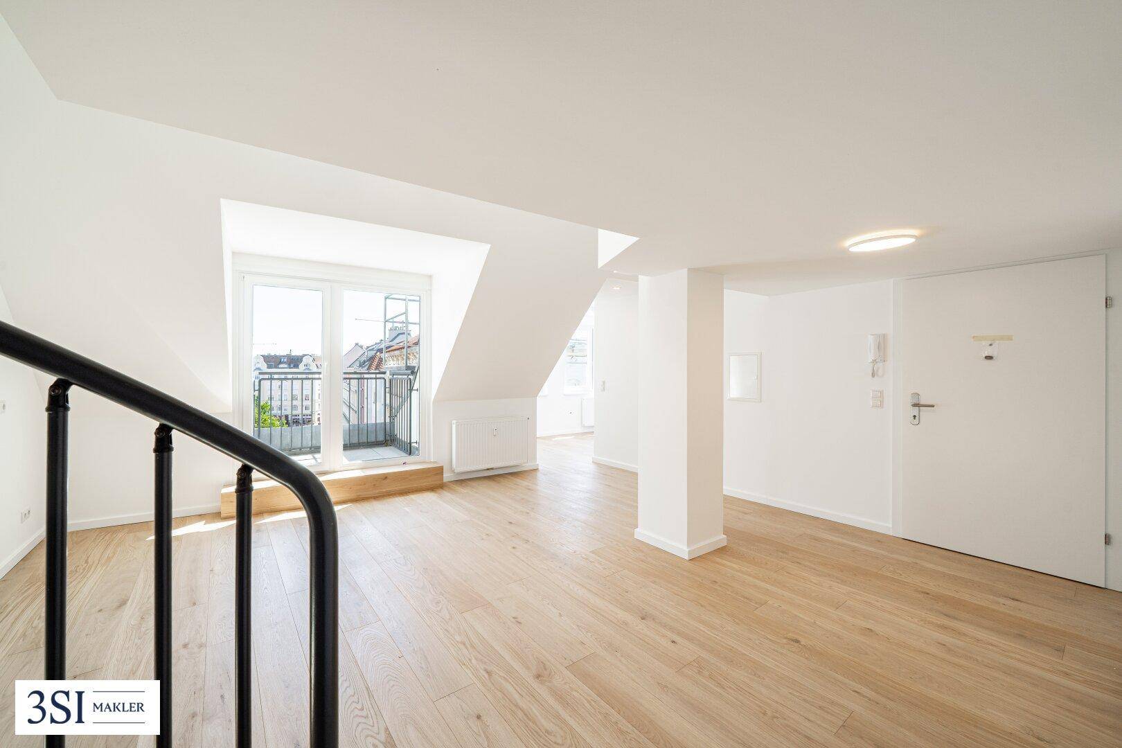 Geräumiges Dachgeschosszimmer mit Holzboden, weiß gestrichenen Wänden und Eingangstür.