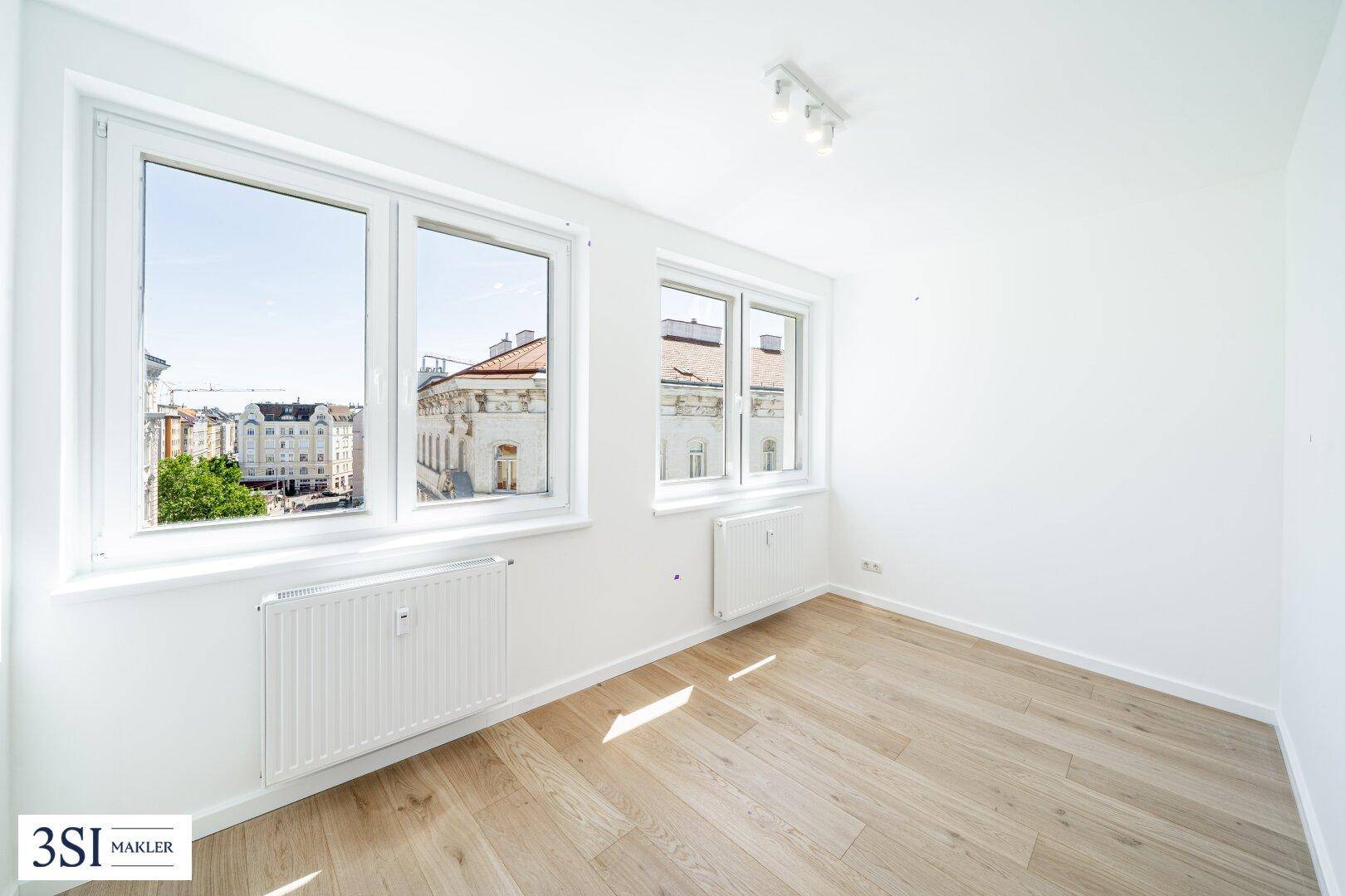 Helles Schlafzimmer mit Holzboden, weißen Wänden und großen Fenstern mit Stadtblick.