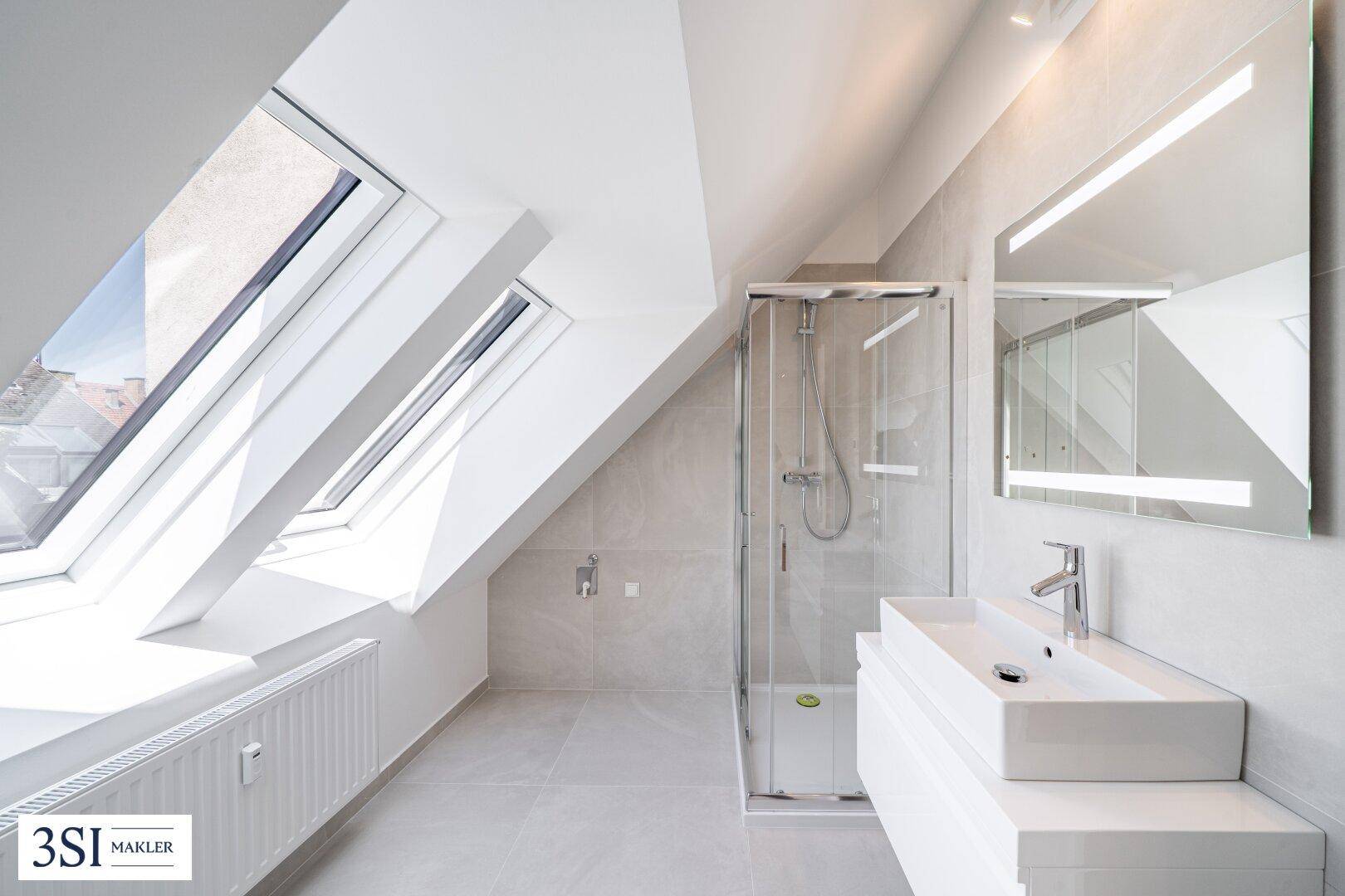 Modernes Badezimmer mit Duschkabine, Einzelwaschbecken, Spiegelschrank und hellen Dachfenstern.