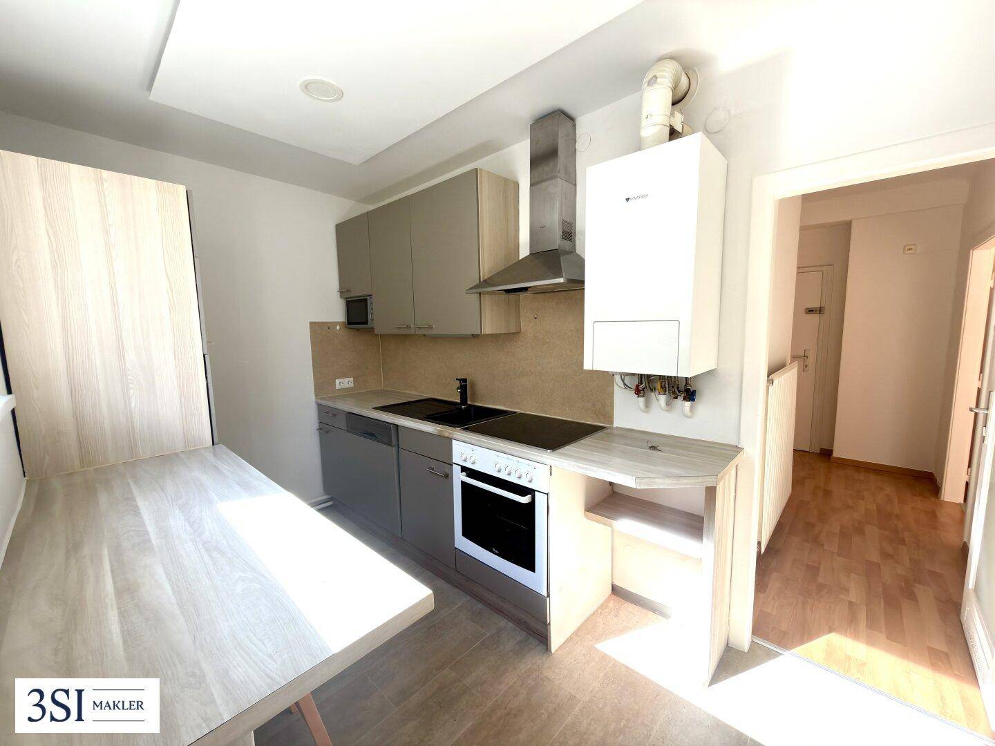 Funktionale Küche mit Einbauschränken, Kochfeld, Backofen und einem Heizkessel an der Wand.