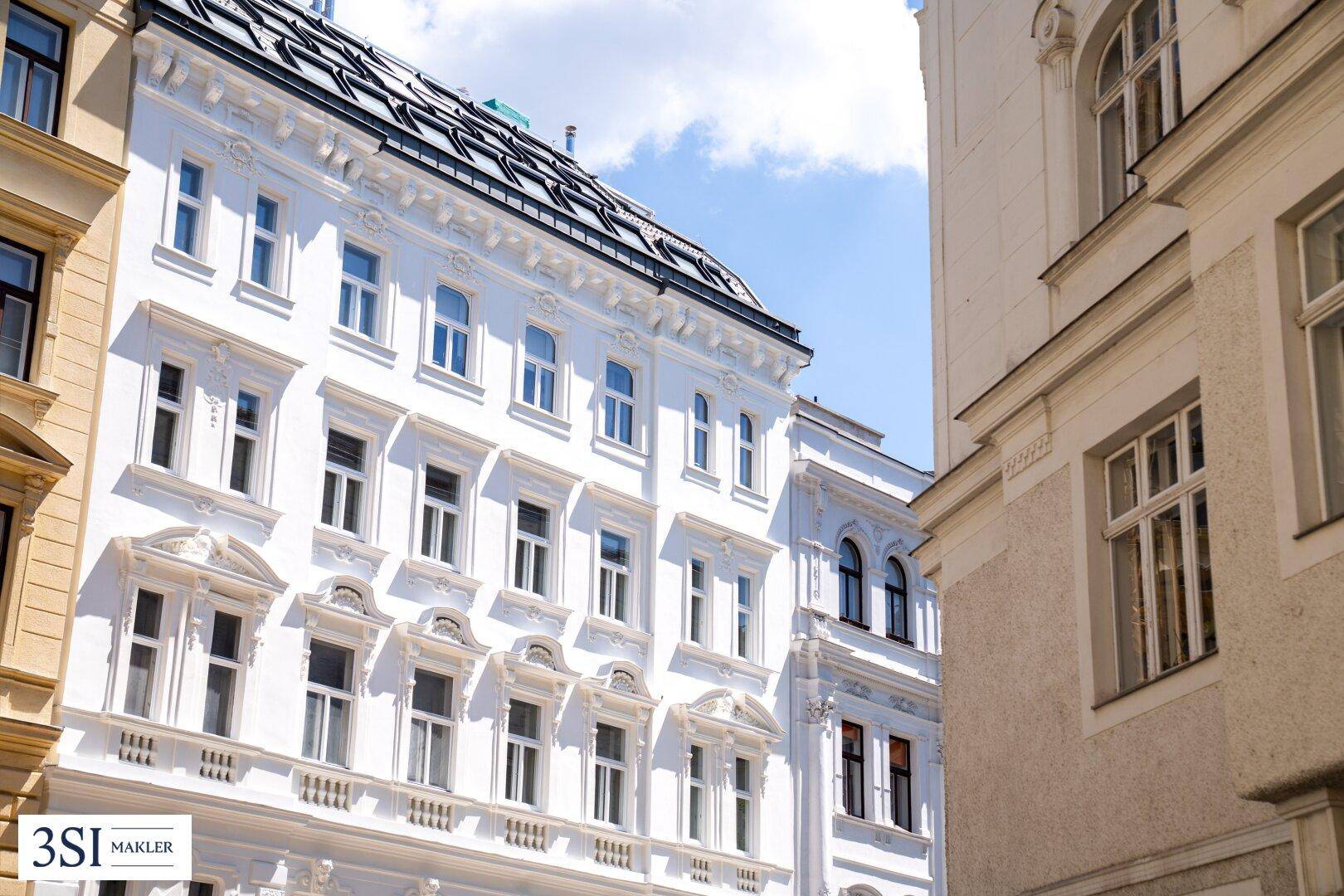 Historische Fassade eines eleganten Gebäudes mit vielen Fenstern und architektonischen Details.