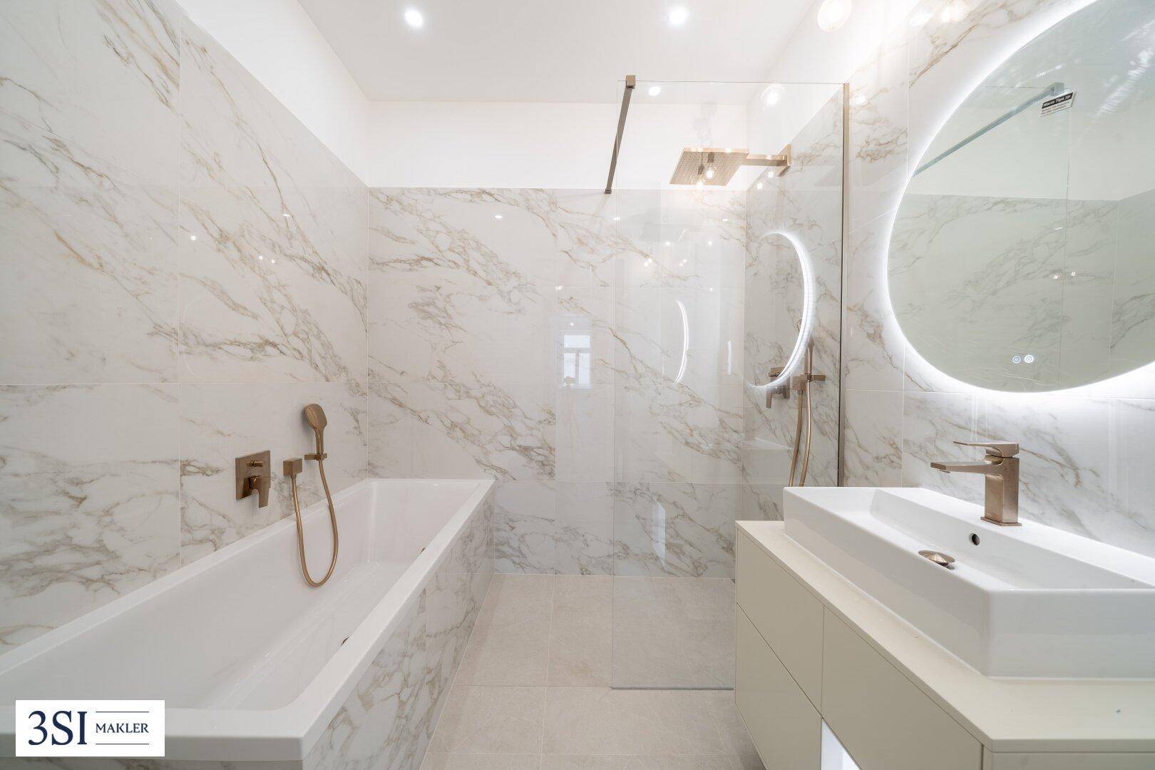 Modernes Badezimmer mit Marmorfliesen, Badewanne, begehbarer Dusche und eleganten Armaturen.