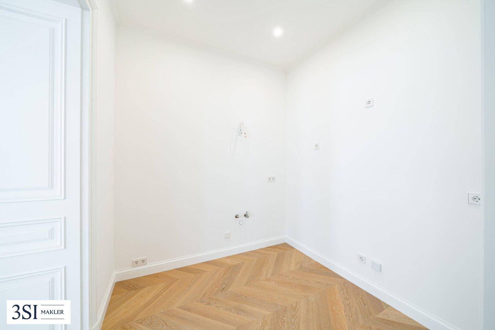 Leerer Raum mit Fischgrätparkett und zahlreichen Steckdosen, ideal als Abstell- oder Hauswirtschaftsraum.