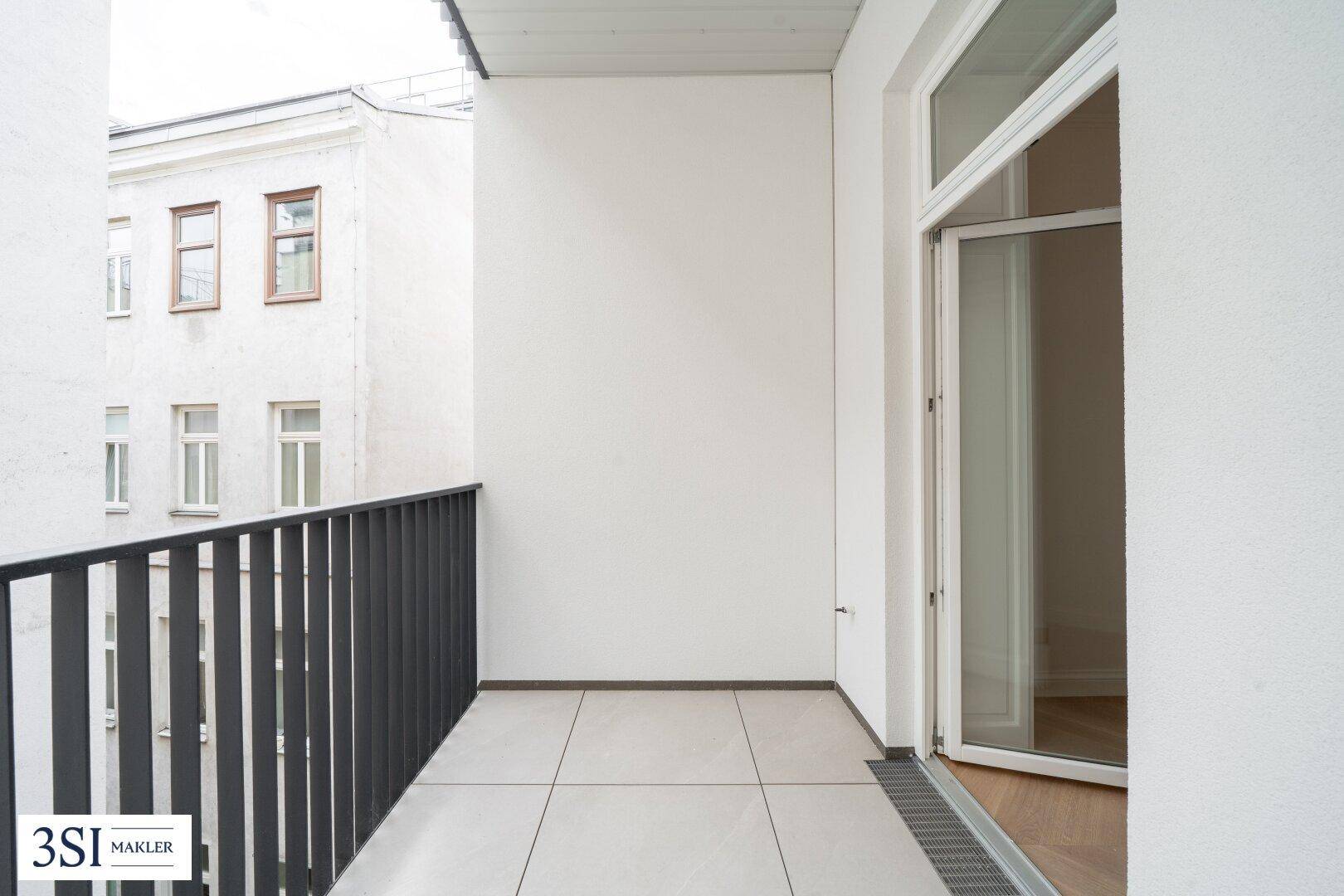 Geräumiger Balkon mit Fliesenboden und Blick auf die umliegenden Gebäude, bereit zur individuellen Gestaltung.