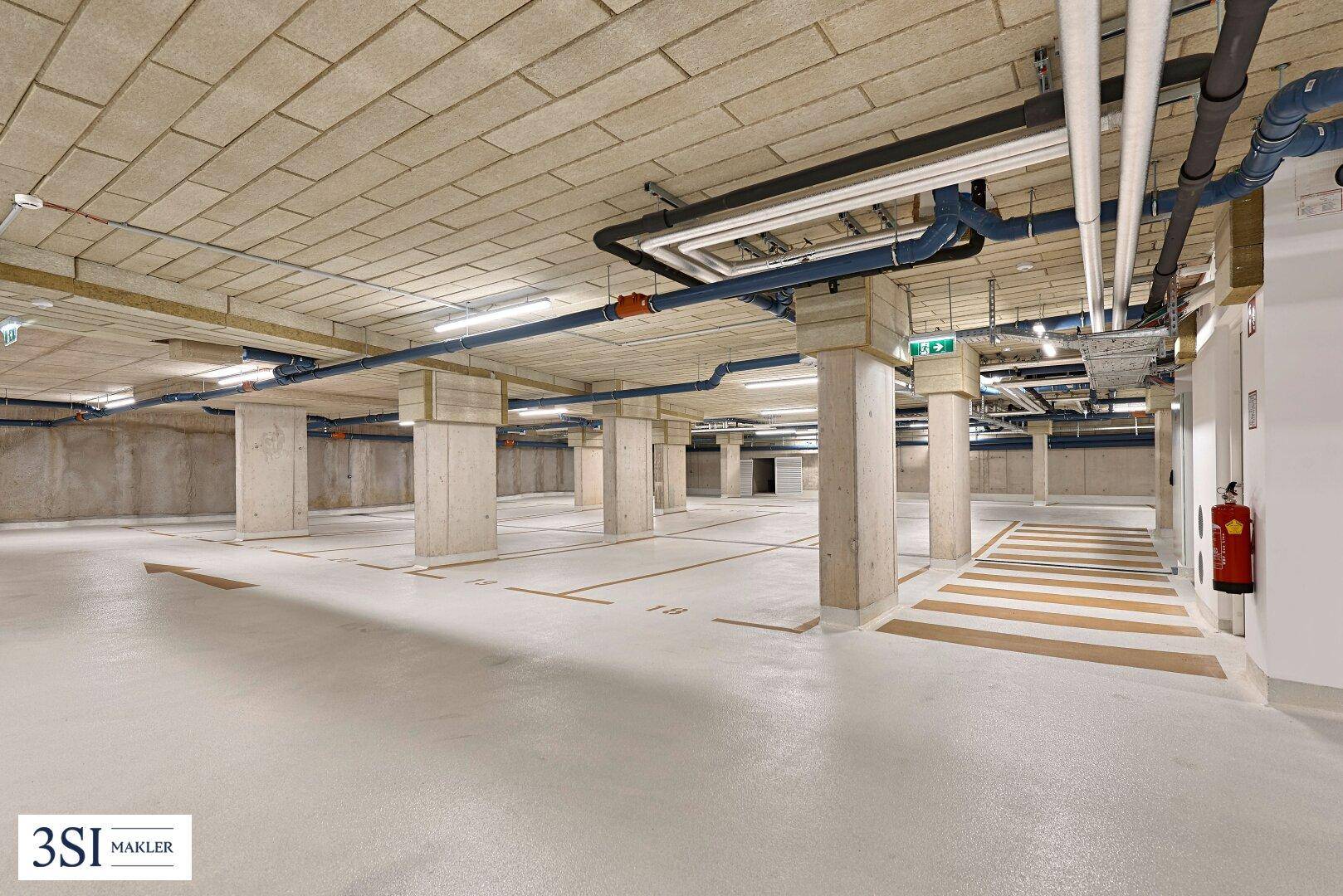Geräumige Tiefgarage mit Betonpfeilern, sichtbaren Leitungen und markierten Parkplätzen.