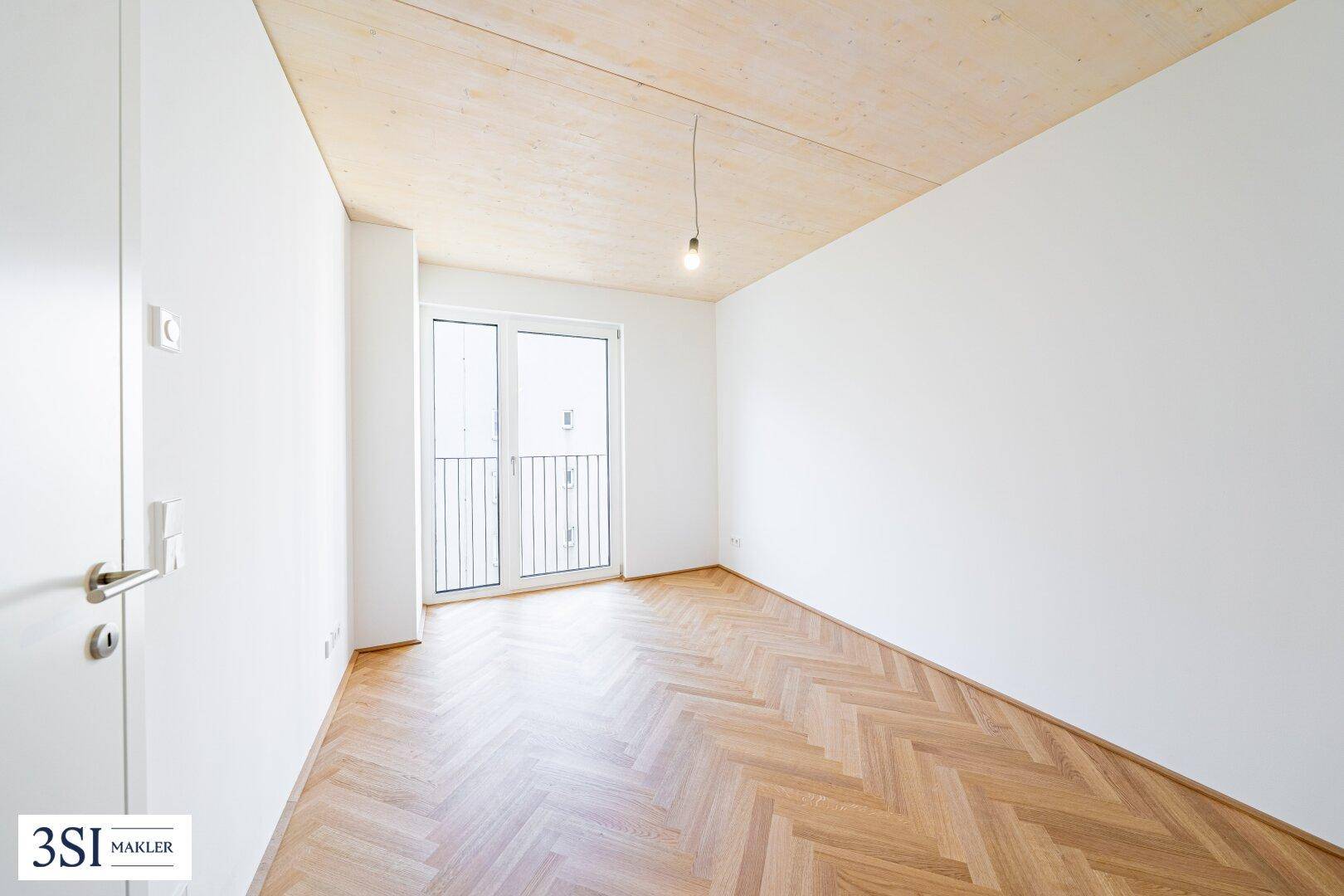 Helles Schlafzimmer mit Fischgrätparkett, Holzbalkendecke und französischem Balkon.