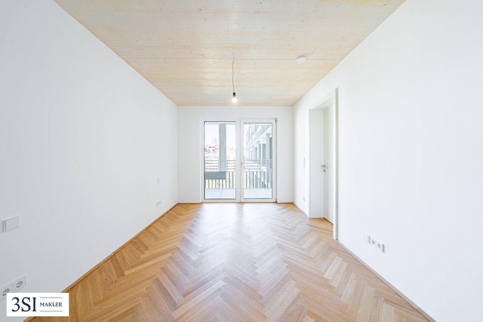 Geräumiges Schlafzimmer mit Fischgrätparkett, Holzbalkendecke und französischem Balkon.