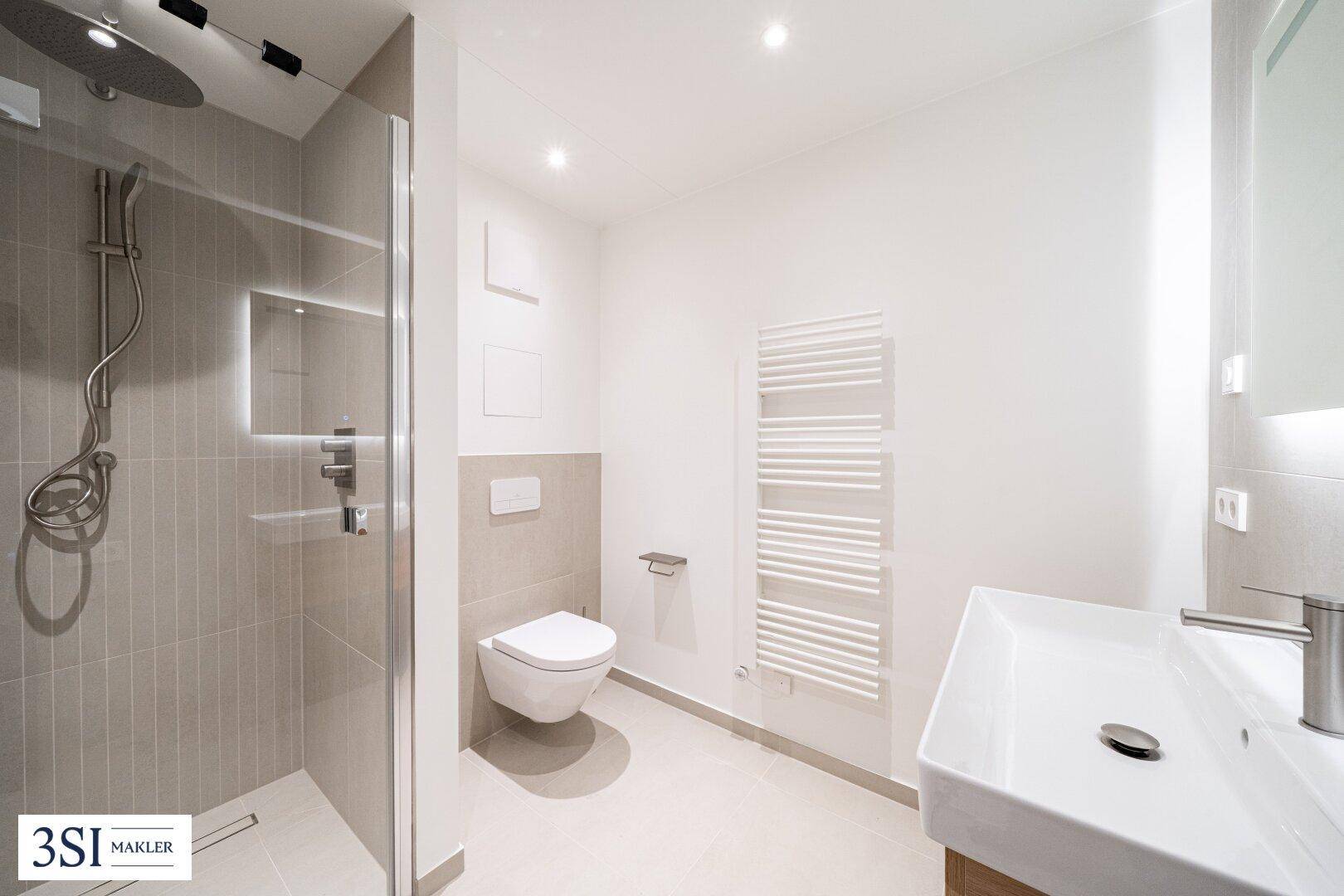 Modernes Badezimmer mit ebenerdiger Dusche, wandhängendem WC und Handtuchheizkörper.