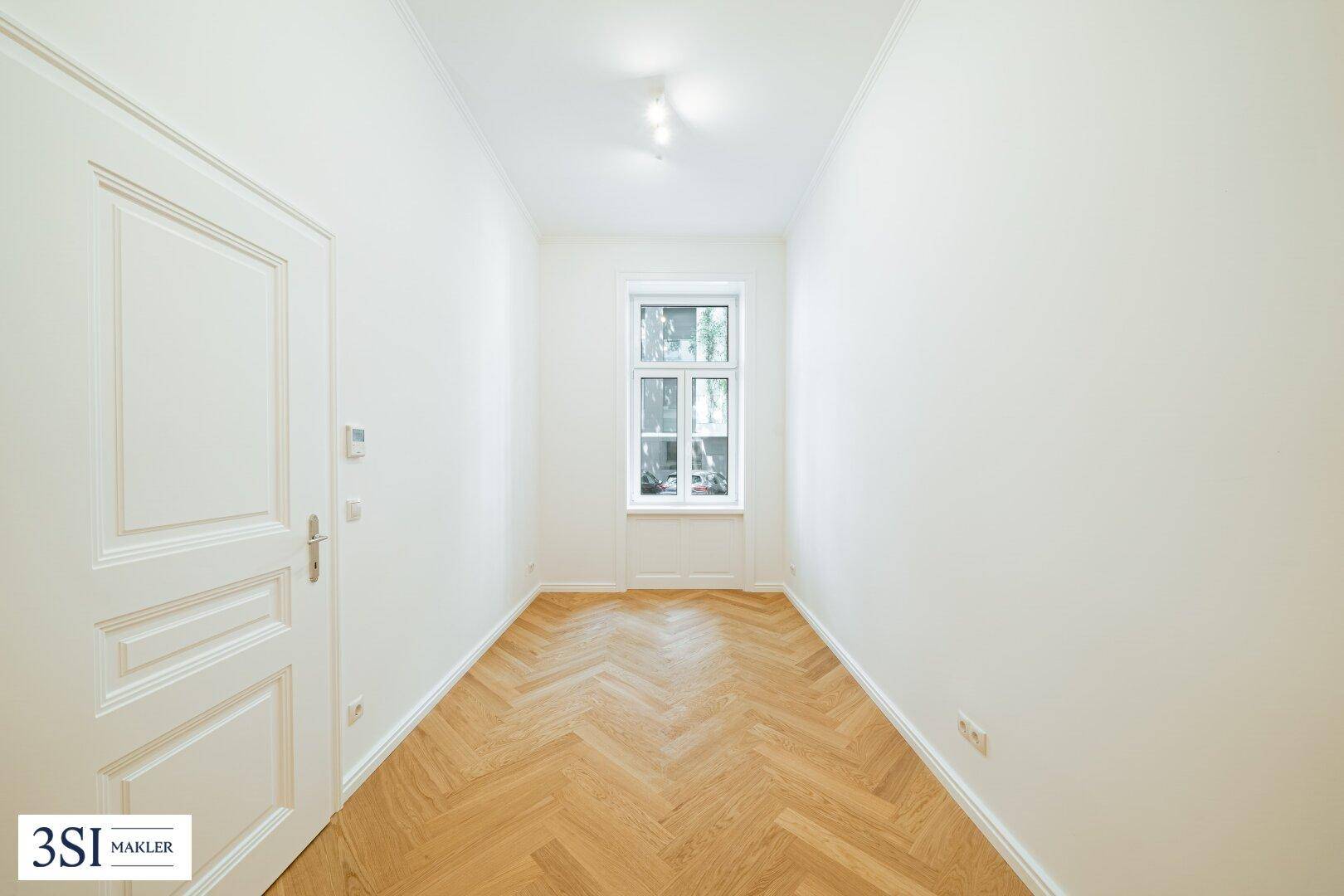 Kleiner, heller Raum mit Fischgrätparkett und einem Fenster, ideal als Büro oder Gästezimmer.