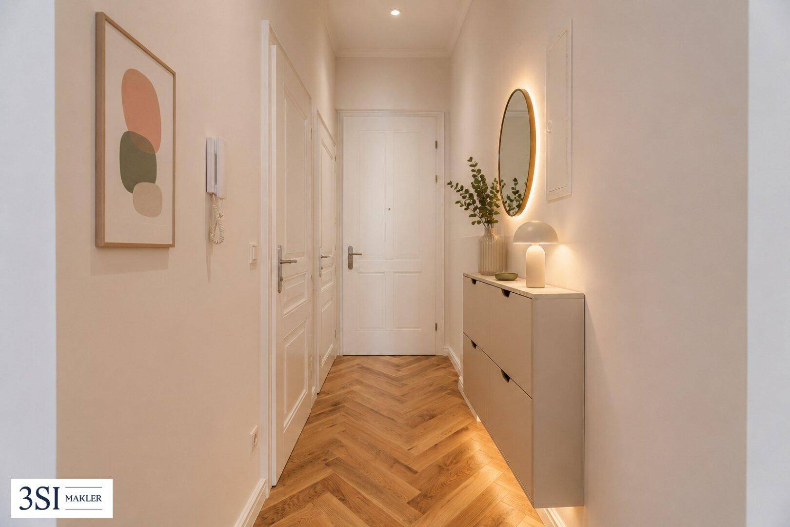 Heller Flur mit Fischgrätparkett, modernem Schuhschrank und dekorativem Spiegel.