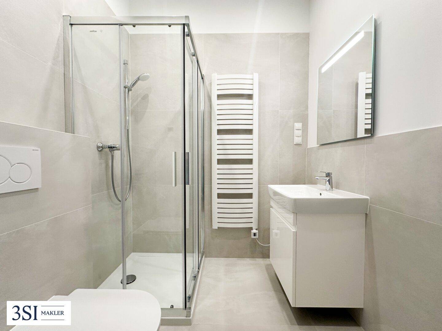 Modernes Badezimmer mit begehbarer Dusche, Wand-WC, Einzelwaschbecken und beheiztem Handtuchhalter.