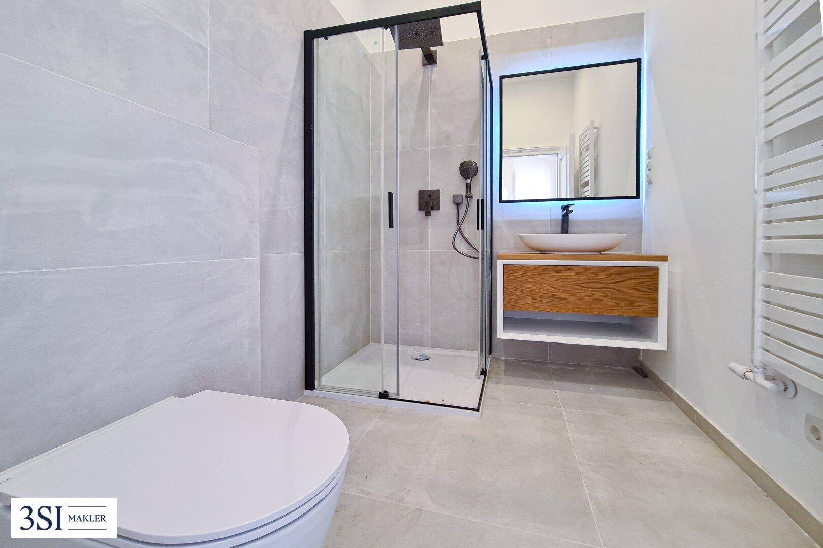 Modernes Badezimmer mit großer Duschkabine, Waschtisch und beheiztem Handtuchhalter.