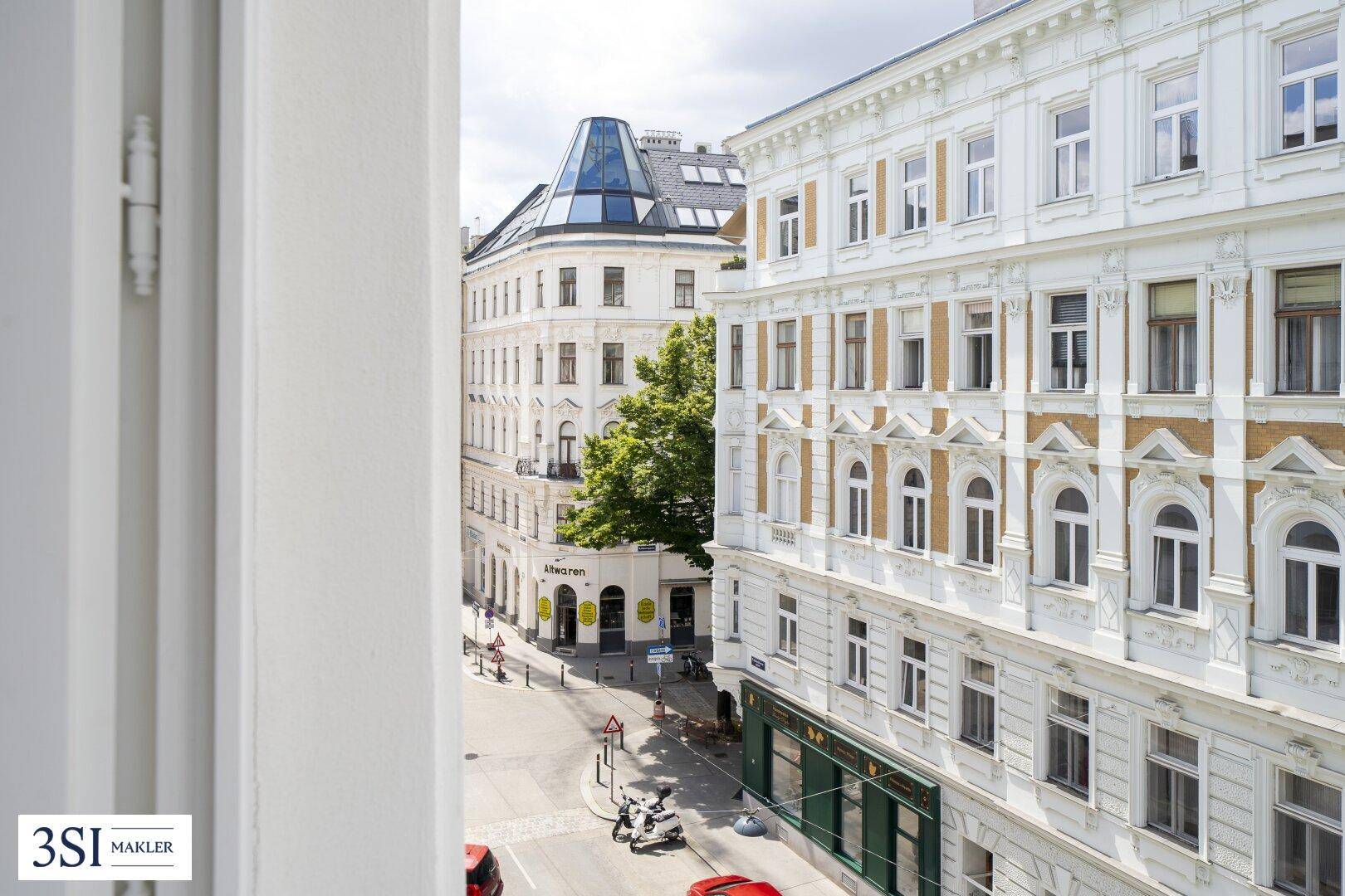 Ausblick auf eine charmante Straßenecke mit klassischer Architektur und einem grünen Baum.