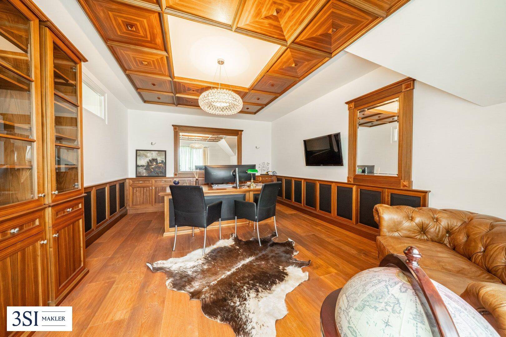 Elegantes Arbeitszimmer mit Holztäfelung, Kassettendecke, Schreibtisch und Ledersofa.