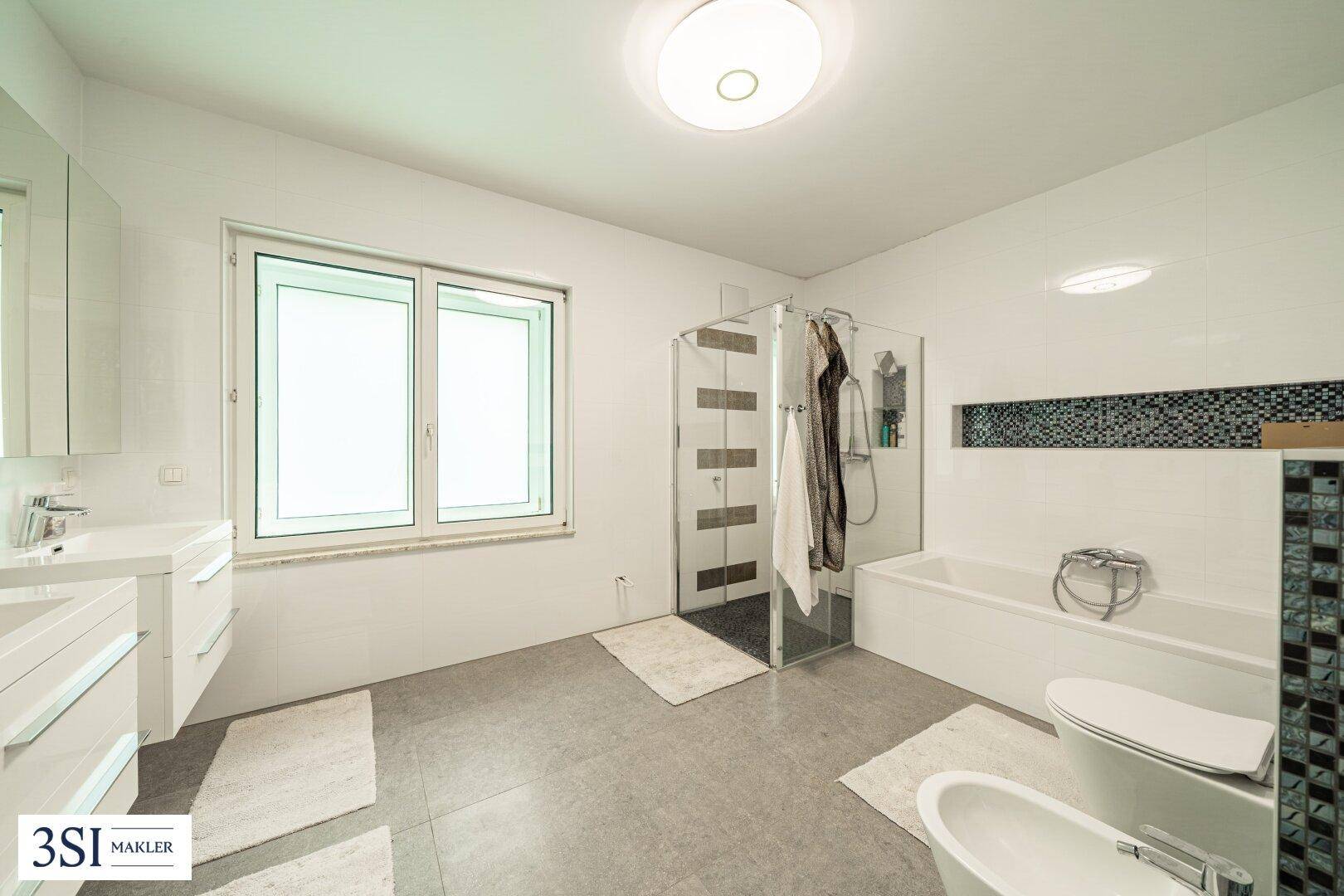 Modernes Badezimmer mit Dusche, Badewanne, Bidet und Doppelwaschbecken.