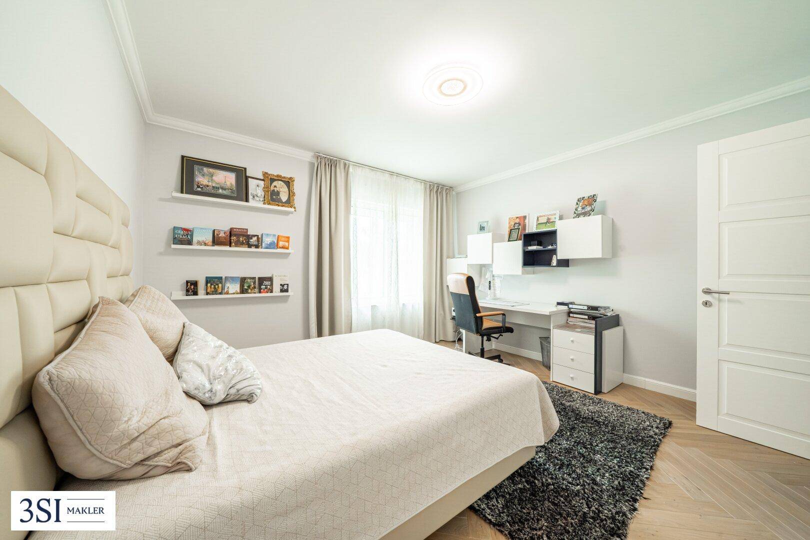 Komfortables Schlafzimmer mit großem Bett, Schreibtisch und Fischgrätparkett.