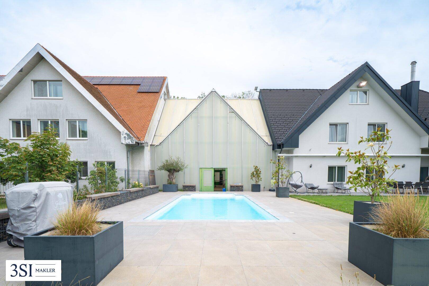 Außenbereich mit Swimmingpool, gepflasterter Terrasse und Blick auf die Gebäudefassaden.