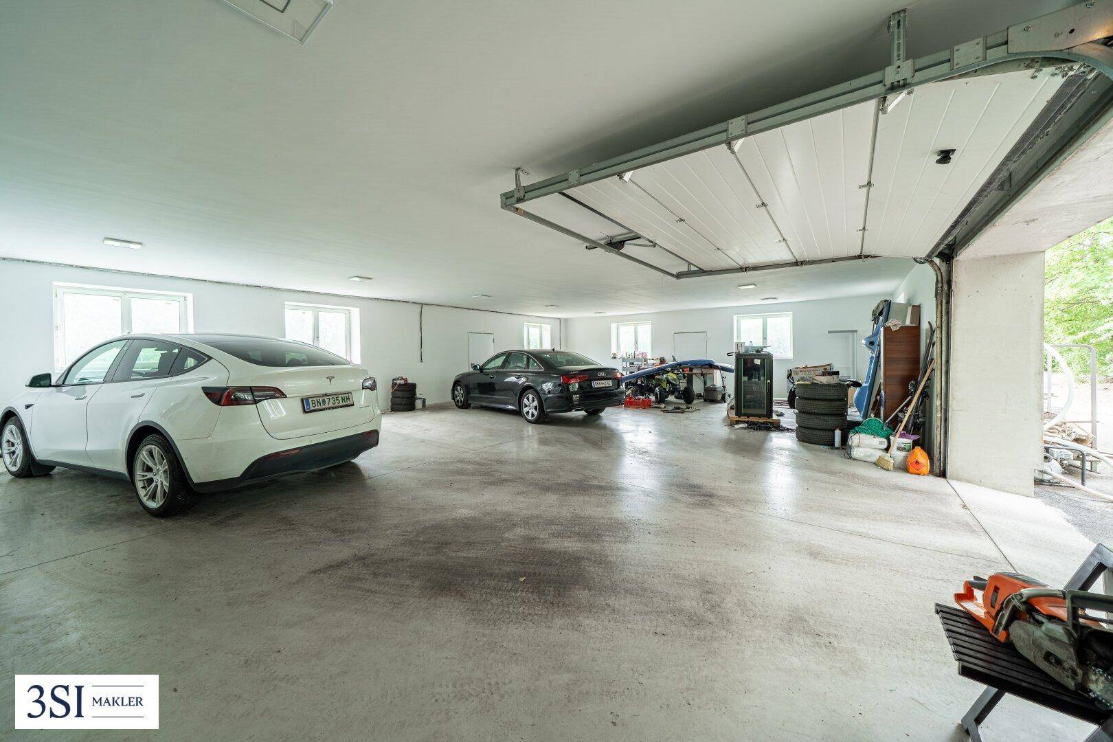 Geräumige Garage mit Platz für mehrere Fahrzeuge und großen Fenstern.