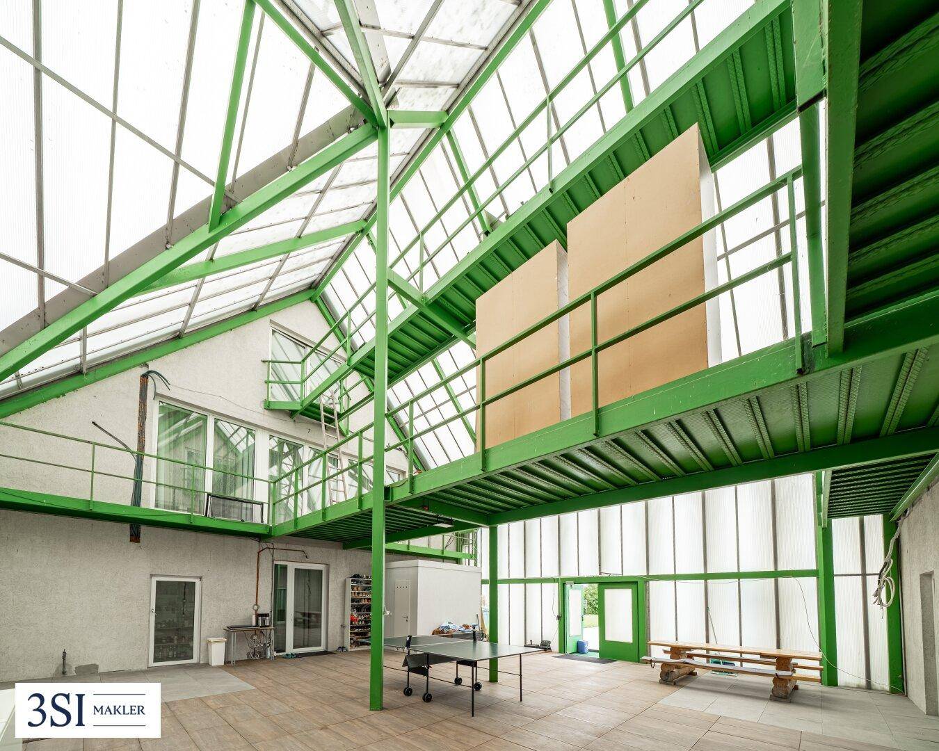 Große, lichtdurchflutete Halle mit Glasdach und Stahlkonstruktion, ideal für verschiedene Aktivitäten.