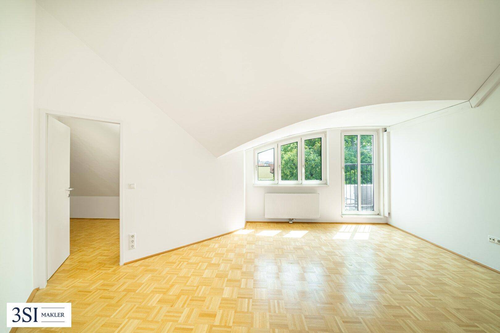Lichtdurchflutetes Zimmer mit Parkettboden, Dachschräge und Zugang zu einem weiteren Raum.