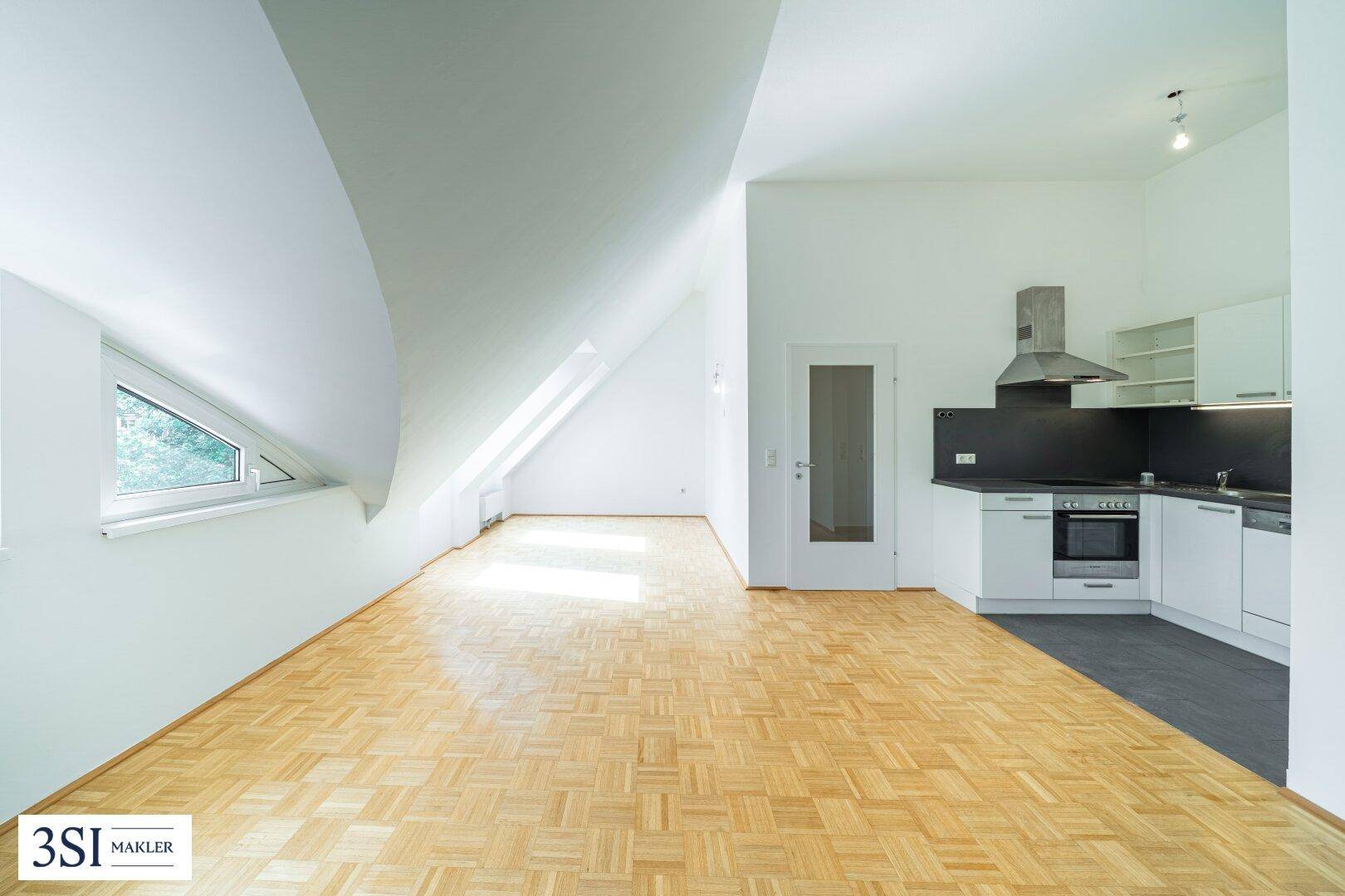 Offener Wohnbereich mit integrierter Küche, Parkettboden und viel Tageslicht durch die Dachfenster.