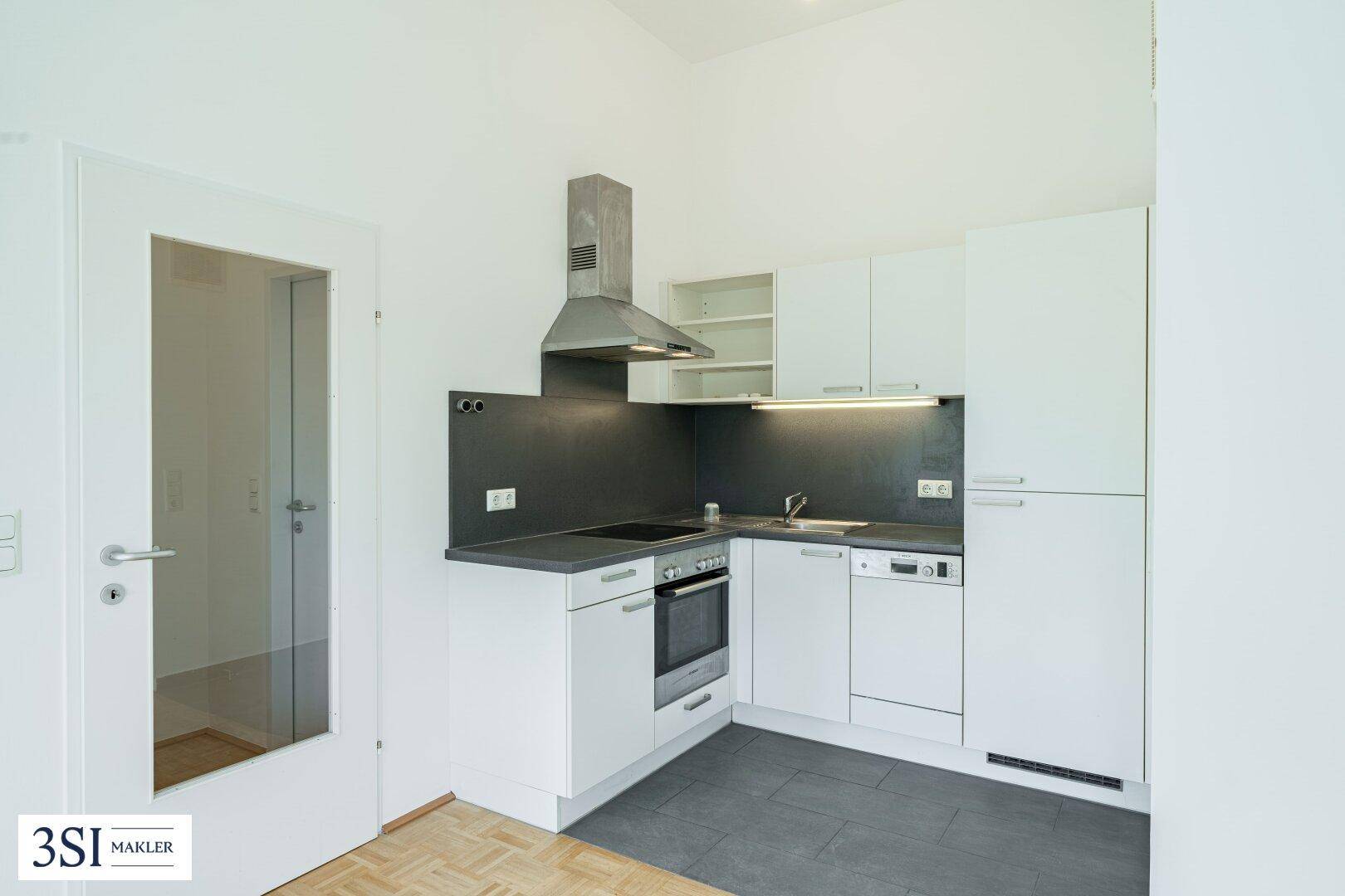 Moderne Einbauküche mit weißen Schränken, dunkler Arbeitsplatte und allen notwendigen Geräten.