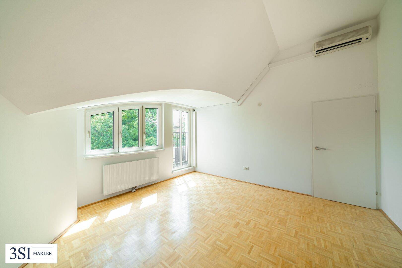 Geräumiges Zimmer mit Parkettboden, Dachschräge und Klimaanlage für angenehme Temperaturen.