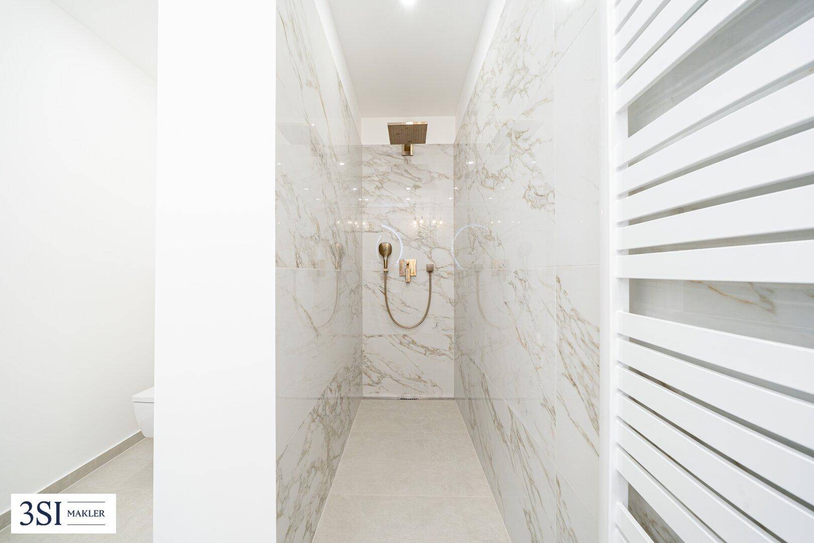 Elegante begehbare Dusche mit Marmorfliesen, goldfarbenen Armaturen und Regenbrause.