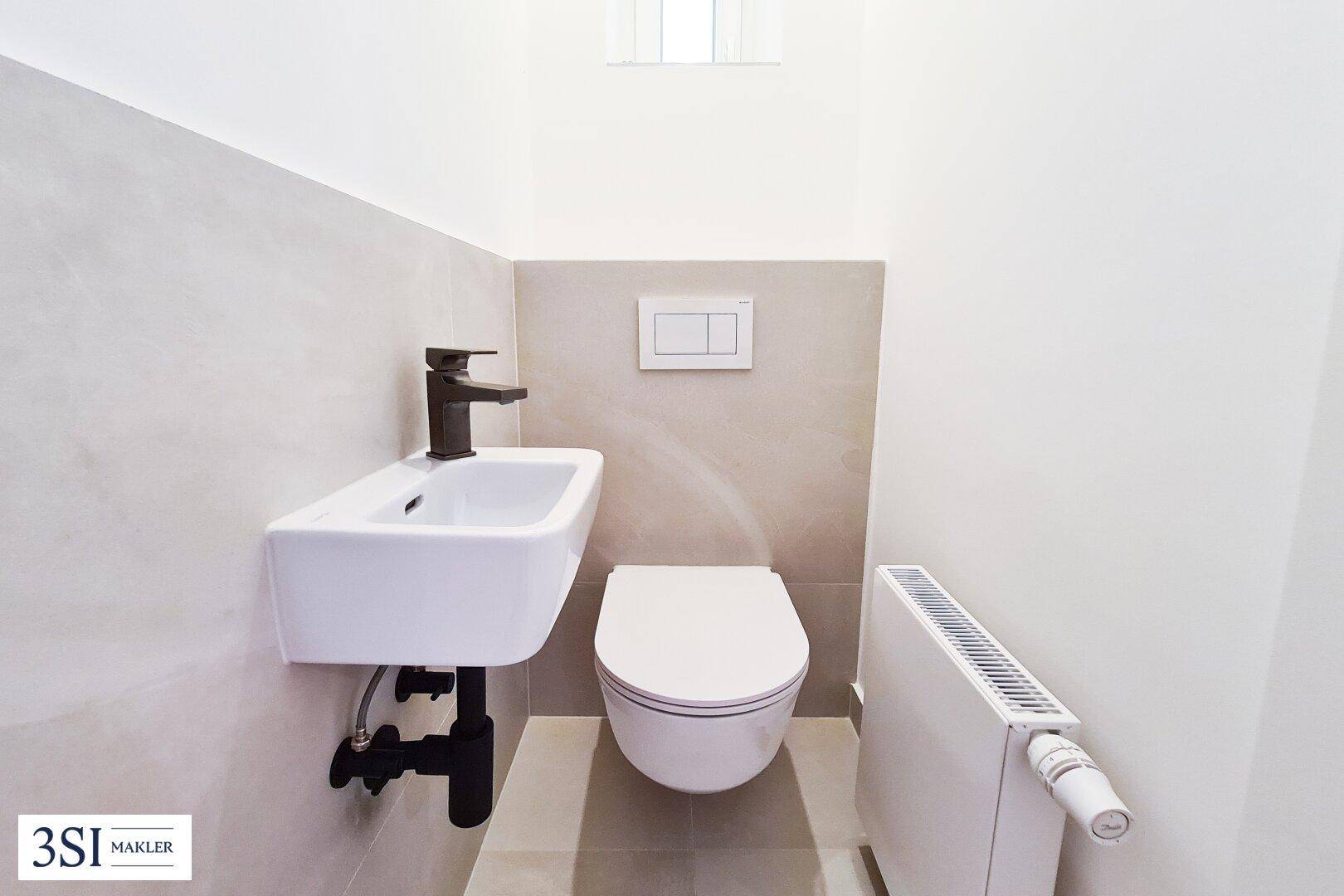 Modernes Gäste-WC mit wandhängender Toilette und kleinem Waschbecken.