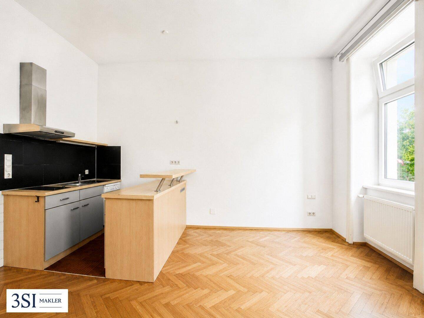Kleine, moderne Küchenzeile mit Kochfeld und Dunstabzugshaube in einem hellen Raum.