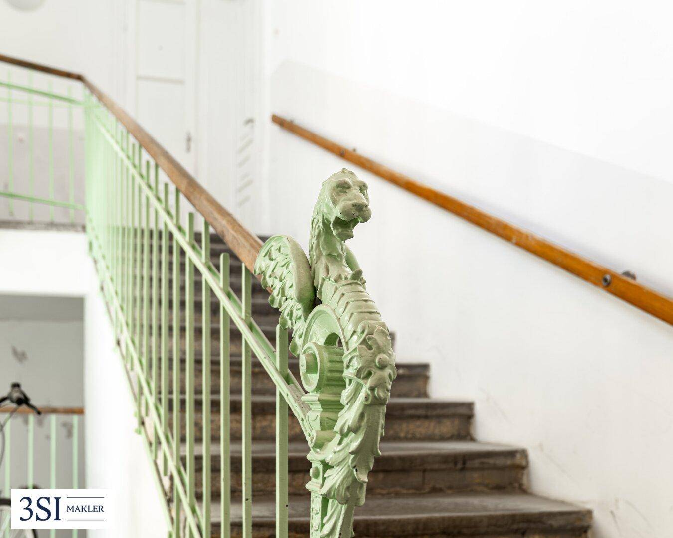 Detailansicht des Treppengeländers mit kunstvollen Verzierungen und einem Holzhandlauf.