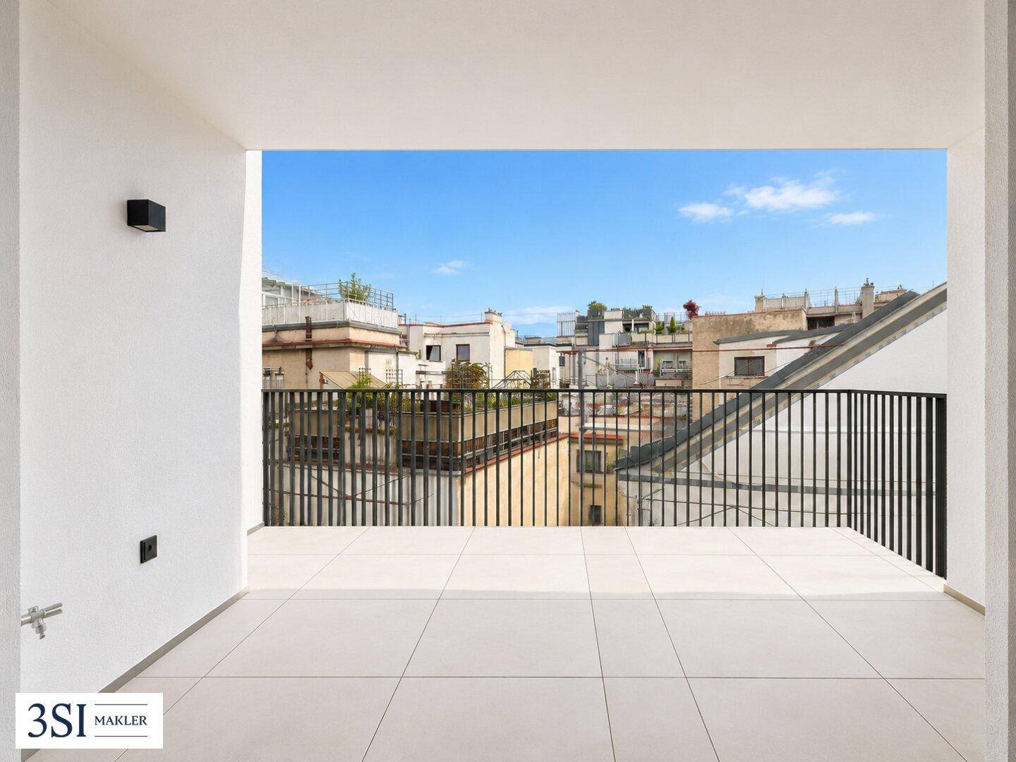 Heller Balkon mit Fliesenboden und Blick über die Dächer der Stadt an einem sonnigen Tag.