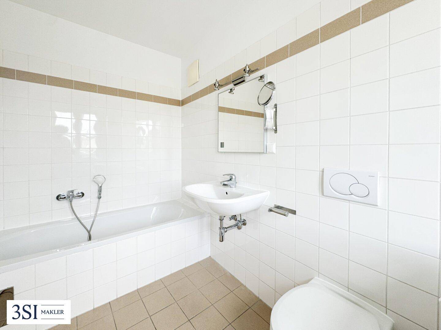 Gefliestes Badezimmer mit Badewanne, Waschbecken und Toilette in hellen Farbtönen.