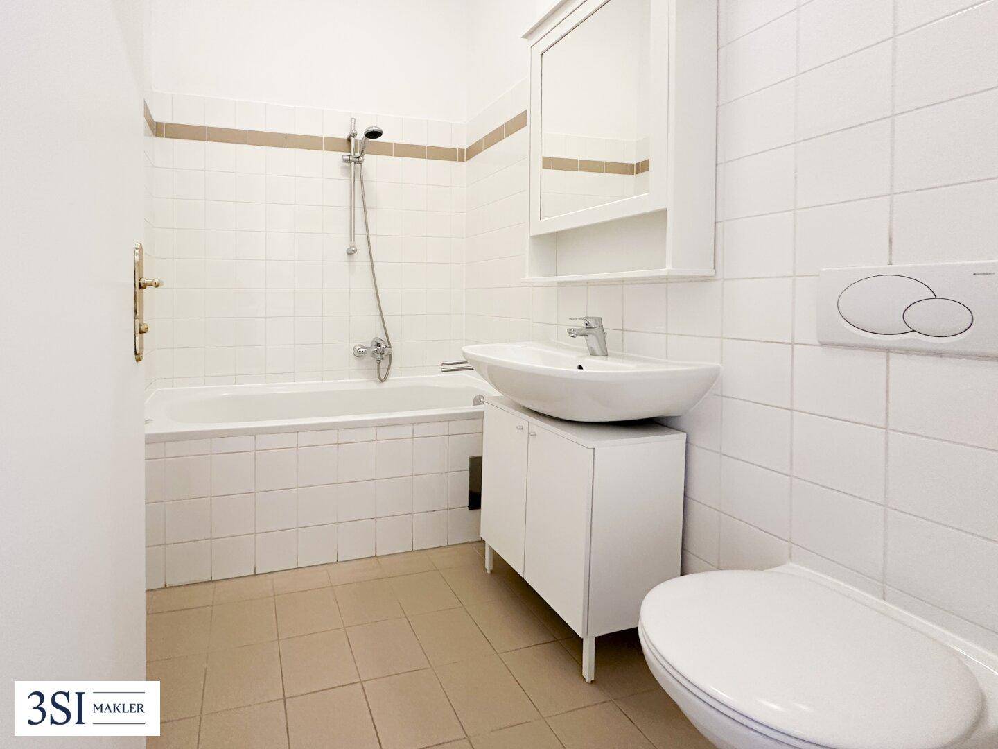 Helles Badezimmer mit Badewanne, Dusche, Waschbecken und WC, ausgestattet mit weißen und beigen Fliesen.
