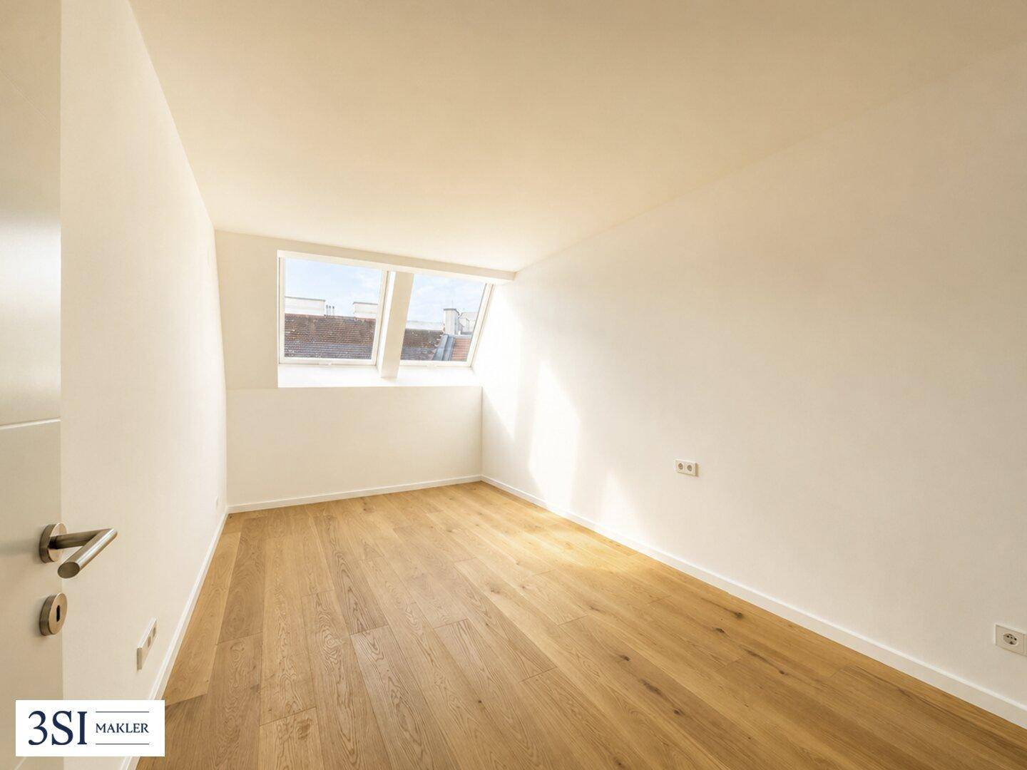 Helles Zimmer mit Holzboden und Dachfenstern, ideal als Schlafzimmer oder Büro nutzbar.