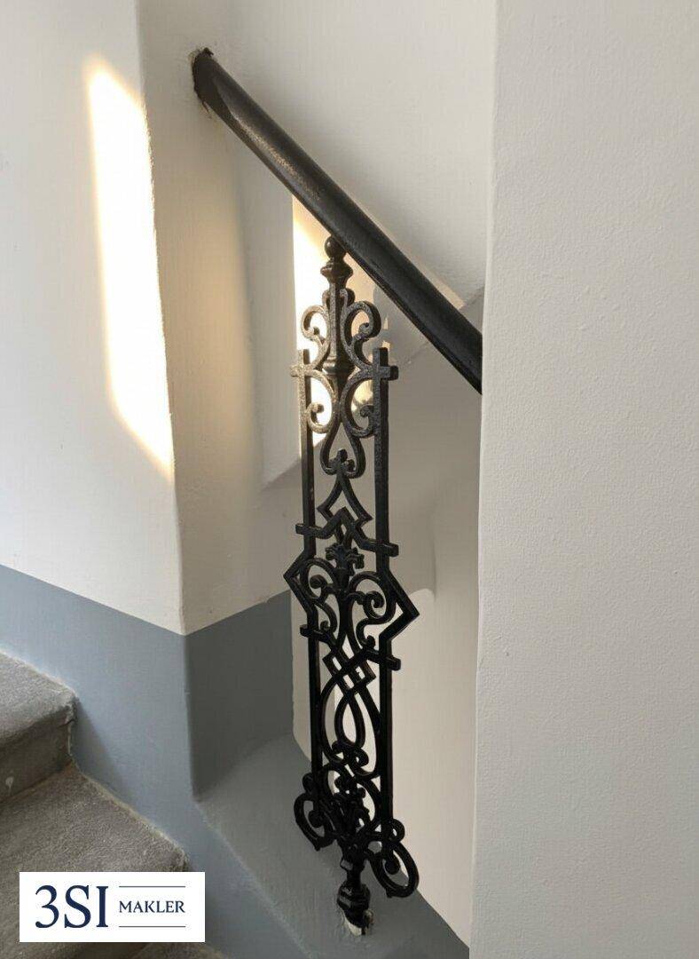 Detailansicht eines kunstvoll geschmiedeten Geländers in einem Treppenhaus mit klassischem Charme.