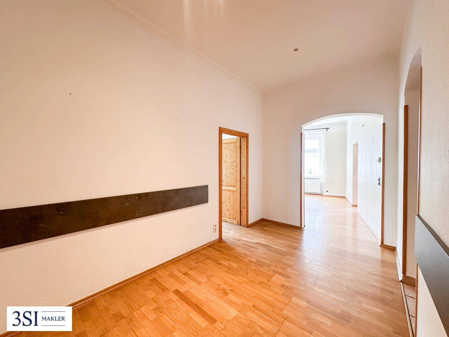 Langer Flur mit Parkettboden und Holztüren, der verschiedene Bereiche der Wohnung verbindet.