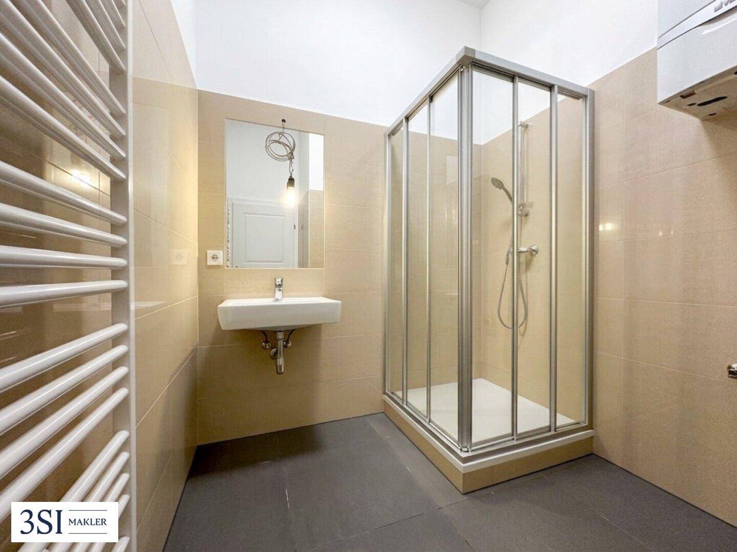 Helles Badezimmer mit Duschkabine, modernem Waschbecken, Spiegel und beheiztem Handtuchhalter.