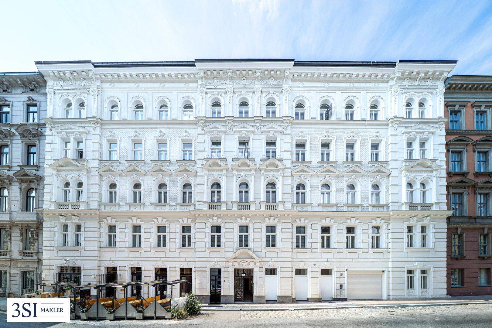 Prächtige weiße Fassade eines historischen Gebäudes mit zahlreichen Fenstern und Verzierungen.