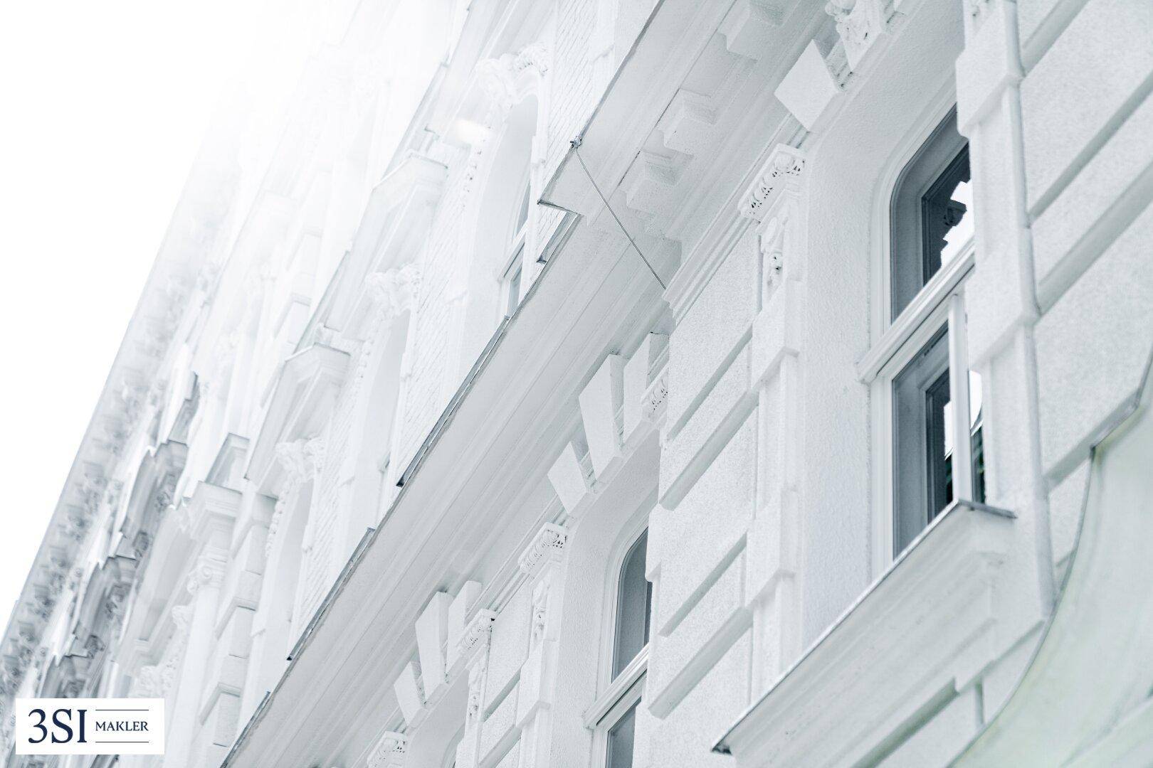 Detailansicht der kunstvollen weißen Fassade mit architektonischen Verzierungen und Fenstern.